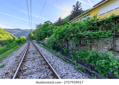 Train track with a house in the background. The train track is empty and the house is yellow