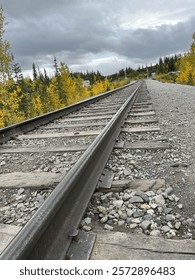 a train track with rocks and trees in the background