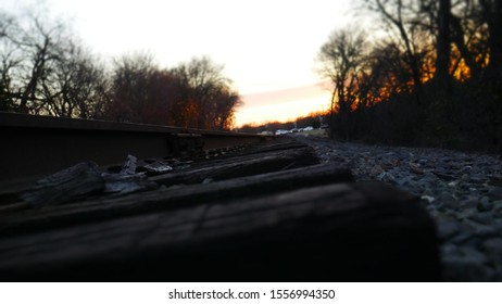 A train track with the sun setting in the background