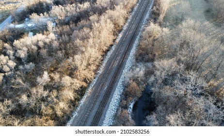 Train Tracks Crossing Forrest With A Small Creek To The Right Of The Tracks. The Photo Was Taken In 4k.