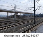 Train Tracks And Elevated Station Platform With Overhead Power Lines Under Clear Sky 