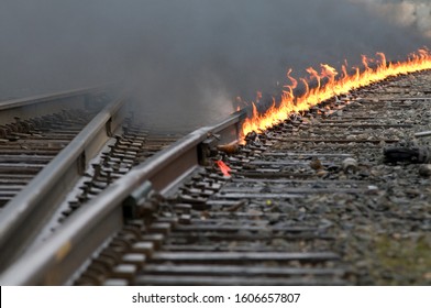 Train Tracks Interchange Leading Around A Curve As A Controlled Fire Burns On The Track During Repairs