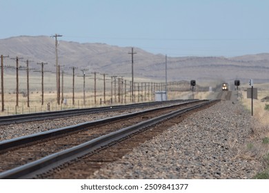 Train tracks looking down the line at a headlight in the distance