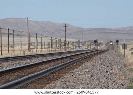 Train tracks looking down the line at a headlight in the distance