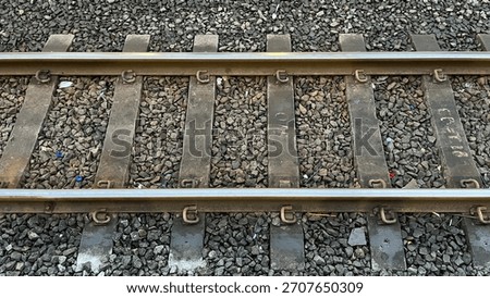 The train tracks are old and rusty. The tracks are covered in gravel and debris. The train tracks are not in use