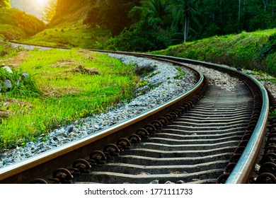 train tracks, railroad, railway, in nature with sunset. The track is curved. Used for transport, passenger trains and tourism, trees and hills on both sides. atmosphere in the morning. - Powered by Shutterstock