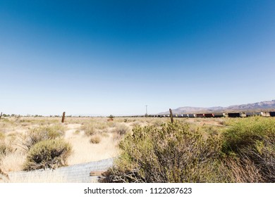 A train transporting containers stretches into the horizon in the hot sun of the Mojave Desert.