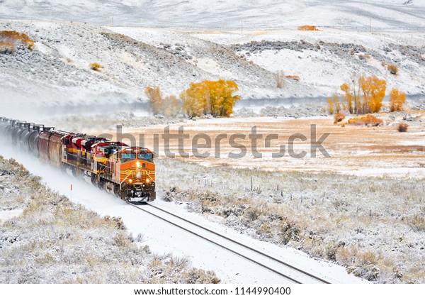 Train\
transporting tank cars. Season changing, first snow and autumn\
trees. Rocky Mountains, Colorado, USA.\
