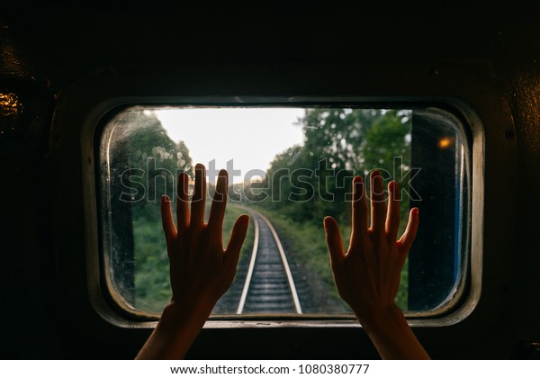 Train travel. Beautiful far scenic view through\
window from riding train at railway with nature ladnscape at\
sunset. Tourist trip. Atmospheric lifestyle journey.  End of\
weekend.  Farewell\
vacation