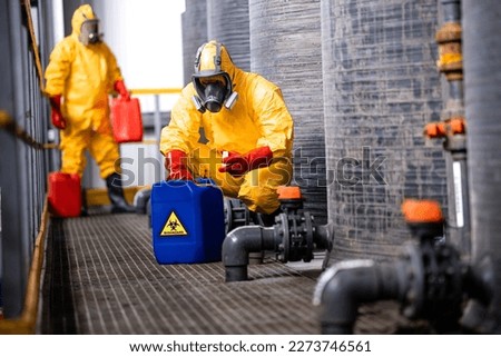 Trained factory workers carefully handling toxic and dangerous biohazardous waste in chemicals factory.