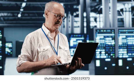 Trained IT professional navigating network of servers in industrial place. Manager with laptop ensuring perfect operations, doing optimizations and maintenance in data center