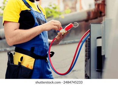 Trained serviceman doing routine condenser maintenance, assembling set of freon barometer starting work. Certified repairman reading pressure of liquids and gases in air conditioning system