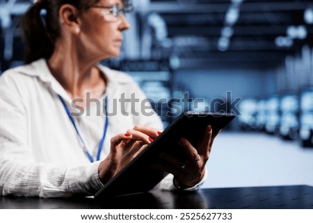 Trained serviceman using tablet to assess server security blips arising due to unsecured network connections. Qualified repairman ensuring data center is impenetrable by malware attacks