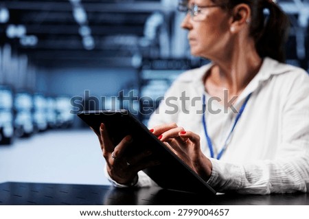 Trained serviceman using tablet to assess server security blips arising due to unsecured network connections. Qualified repairman ensuring data center is impenetrable by malware attacks.