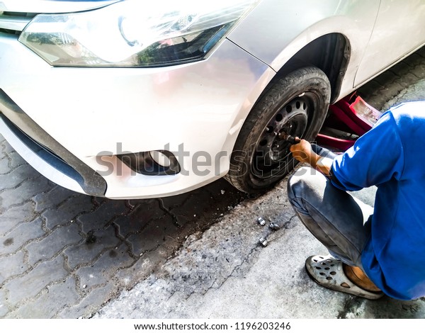 Trainee car mechanic changing car in shop auto\
repair service.,Mechanic changing car wheel in auto repair\
shop.,soft focus.