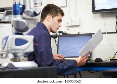 Trainee Engineer Studying Plans With CMM Arm In Foreground