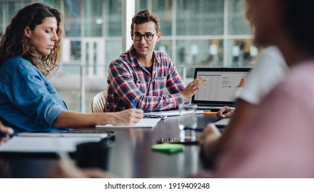 Trainee Professional Showing His Proposal On Laptop To Team In Boardroom. Businessman Giving His Presentation Over Laptop To Colleagues In Office.