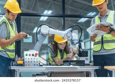 Trainees analyze technical blueprint, program, control robotic arm during practical learning lesson in robot system programming at a manufacturing academy. Emphasizing hands-on experience and skills.