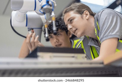 Trainees intensely focus on robot arm, interact with automation programs, analyze robotic components, and practice essential skills as part of manufacturing robotic academy's research and development