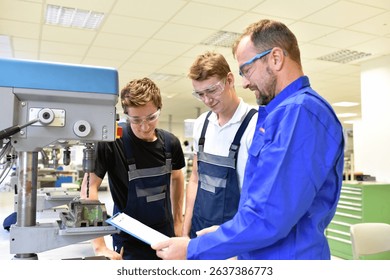 trainer and apprentice in technical vocational training at a drilling machine 