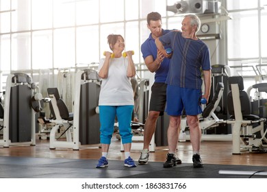 Trainer assisting senior man lifting dumbbell in gym. Senior people with personal fitness trainer. Healthy lifestyle, people and sport concept. - Powered by Shutterstock