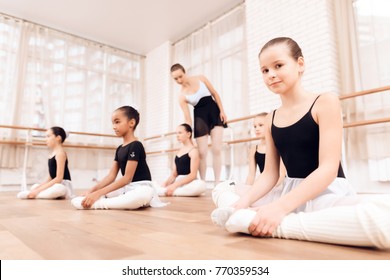 The Trainer Of The Ballet School Helps Young Ballerinas Perform Different Choreographic Exercises. They Rehearse In The Ballet Class. The Teacher Communicates With The Children.