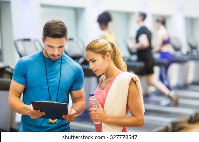 Trainer and client discussing her progress at the gym - Powered by Shutterstock