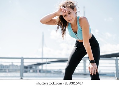 The trainer counts the pulse on a smart watch. Sports and clothing for women. Fitness break in the city. Cardio training for weight loss. The athlete leads a healthy lifestyle.