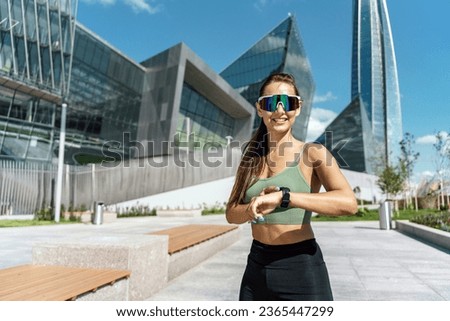 A trainer doing a workout warm-up for running. Interval training in the afternoon. A woman in sports glasses and sportswear.  A confident person is motivated to an active lifestyle.