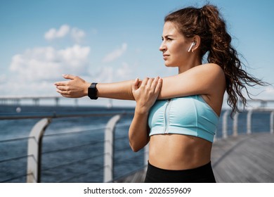 The trainer is engaged in fitness on the street. A smart watch on your hand for counting calories.A sporty woman does exercises in the open air. Healthy lifestyle, sports activities in the city. - Powered by Shutterstock