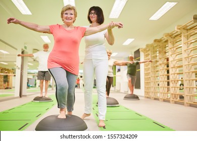 Trainer gives senior help with balance training at the Bosu Ball in the fitness class - Powered by Shutterstock