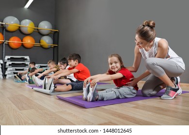Trainer helping children to do physical exercise in school gym. Healthy lifestyle