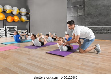 Trainer helping children to do physical exercise in school gym. Healthy lifestyle - Powered by Shutterstock