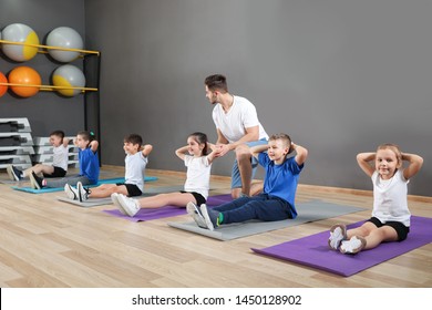 Trainer helping children to do physical exercise in school gym. Healthy lifestyle - Powered by Shutterstock