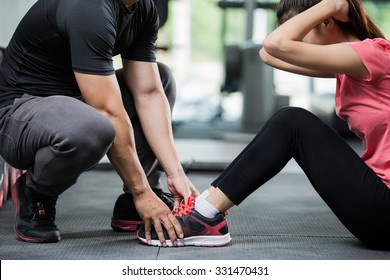 Trainer holding a woman in the leg exercise by Sit-up.