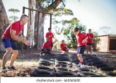 Trainer instructing kids during tyres obstacle course training in the boot camp - Powered by Shutterstock