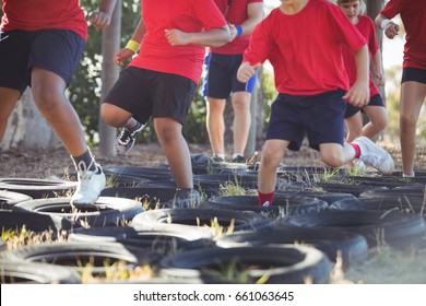 Trainer instructing kids during tyres obstacle course training in the boot camp