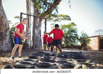 Trainer instructing kids during tyres obstacle course training in the boot camp - Powered by Shutterstock