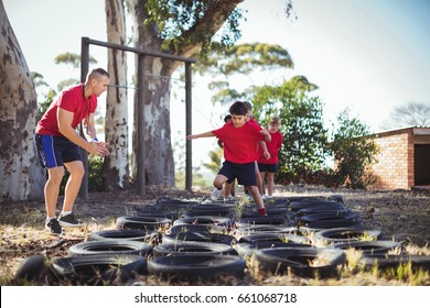 Trainer instructing kids during tyres obstacle course training in the boot camp - Powered by Shutterstock