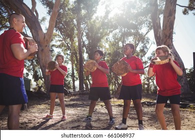 Trainer and kids carrying wooden logs during obstacle course training in the boot camp - Powered by Shutterstock