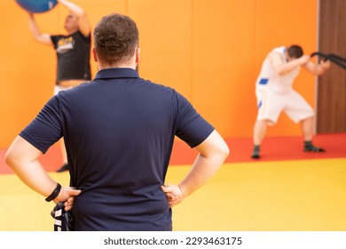 trainer looking at men exercising