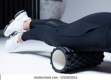 The trainer massages the muscles of the hips and legs, anterior thigh muscle before starting training with a black massage roller - Powered by Shutterstock