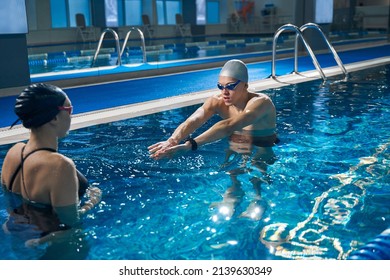 Trainer showing woman how to swim in pool - Powered by Shutterstock