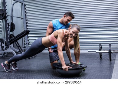 Trainer supervising a muscular woman doing bosu ball exercises - Powered by Shutterstock