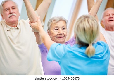 Trainer supports seniors in gymnastics for the back in physiotherapy - Powered by Shutterstock