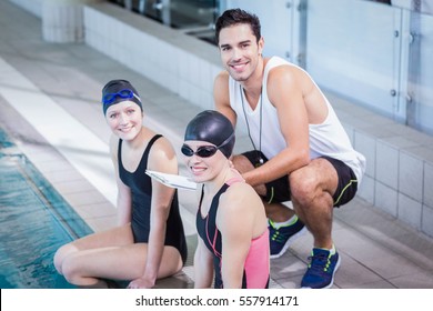 Trainer and swimmers smiling at the camera at the leisure center - Powered by Shutterstock