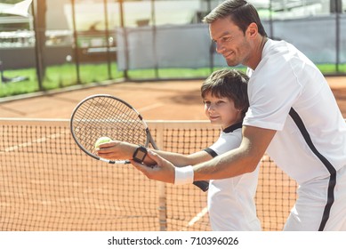 Trainer Teaching Boy To Play Tennis