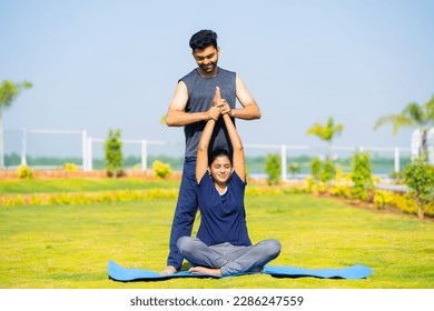 Trainer teaching yoga pose or posture to girl at park - concept of yoga guru, personal coach and Professional occupation. - Powered by Shutterstock