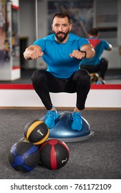 Trainer working with a balance ball (bosu) in the gym