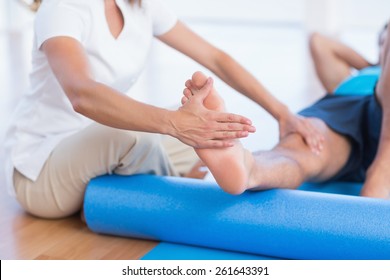 Trainer working with man on exercise mat in fitness studio - Shutterstock ID 261643391